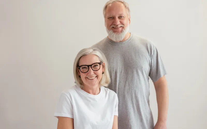 Casal de idosos sorrindo lado a lado.