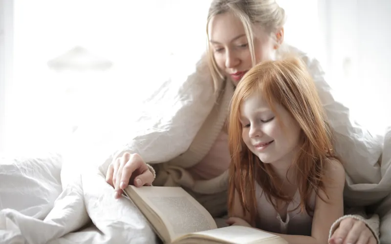 Mãe e filha compartilhando a leitura de um livro.